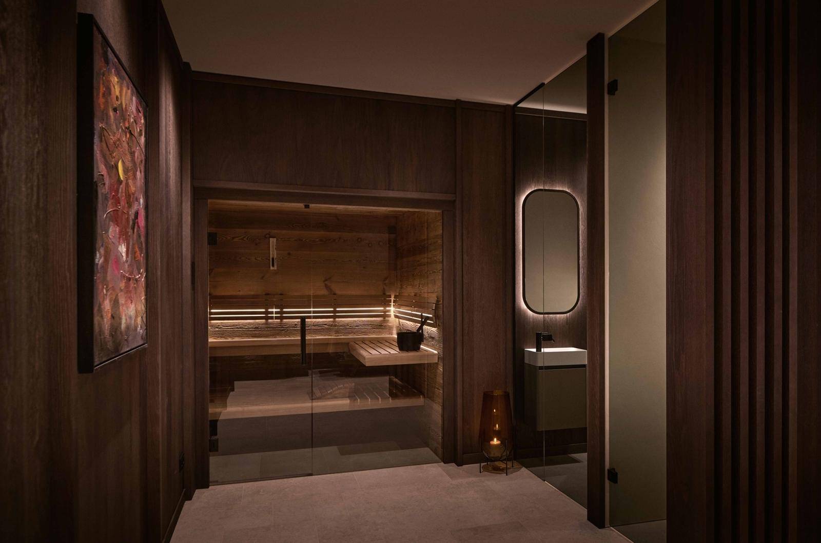 Exklusiver Wellnessbereich mit Sauna und modernem Waschbecken in dunklem Holzdesign.