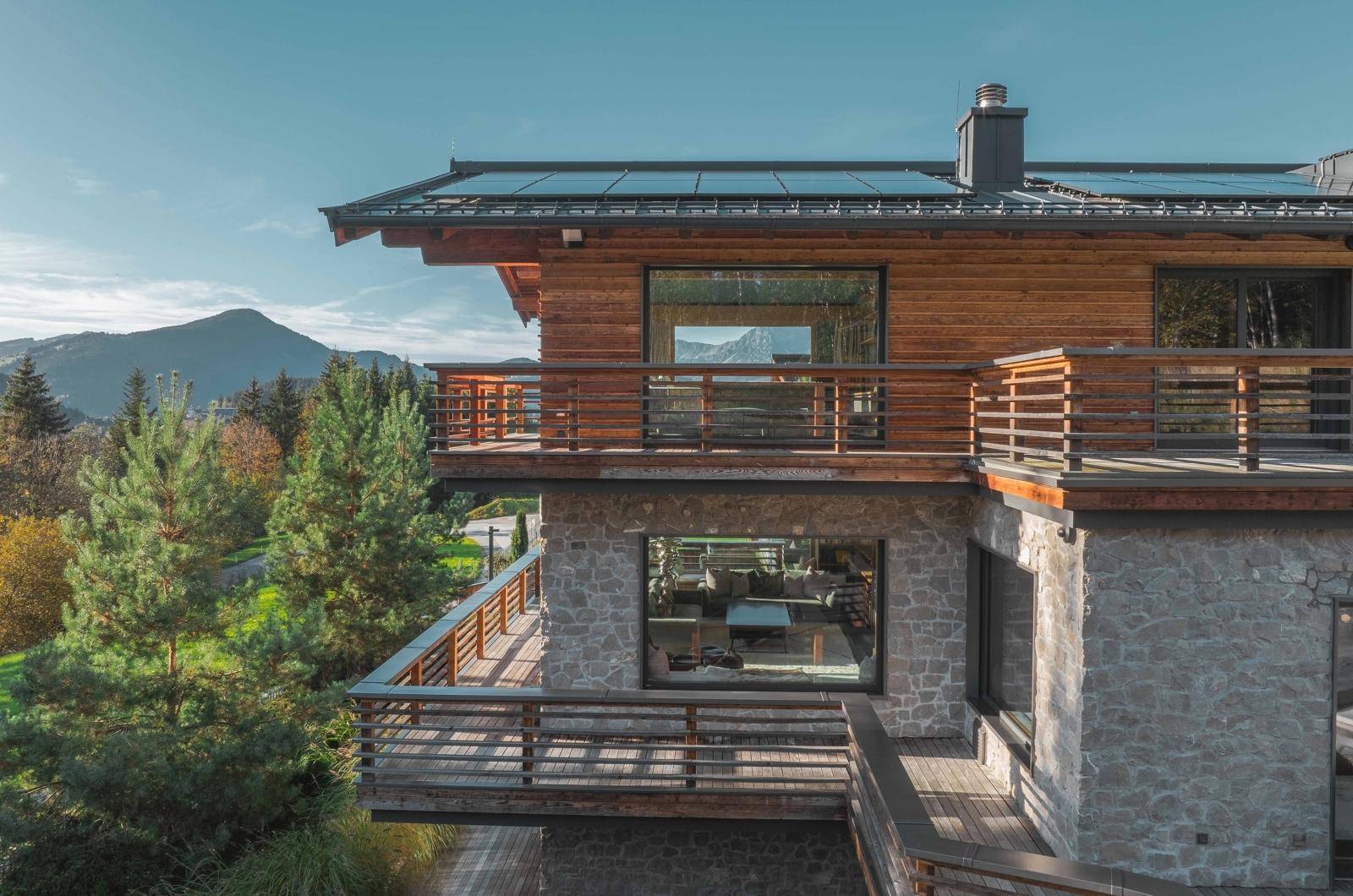 Eindrucksvolles Chalet mit Stein- und Holzfassade, mehreren Balkonen und einem atemberaubenden Bergblick.