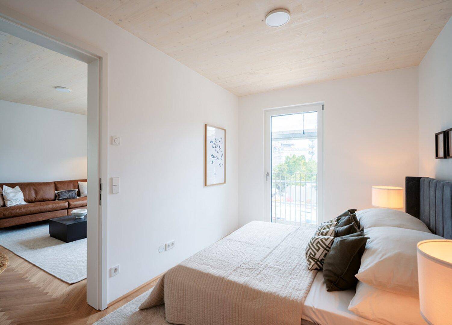 Gemütliches Schlafzimmer mit Holzbalkendecke, Parkettboden und Zugang zu einem französischen Balkon.
