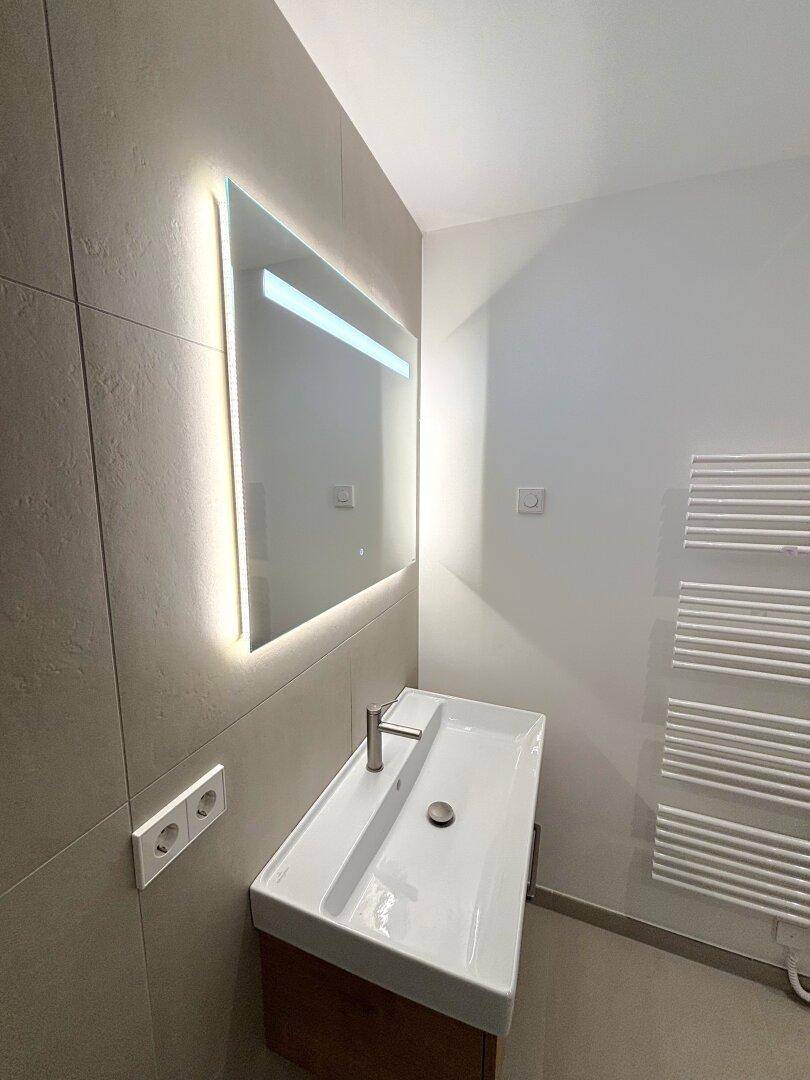 Stilvoller Waschtisch mit beleuchtetem Spiegel und modernem Design im Badezimmer.
