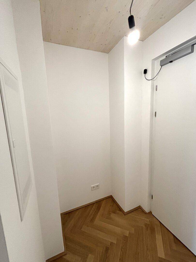 Heller Eingangsbereich mit Fischgrätparkett und weiß gestrichenen Wänden.