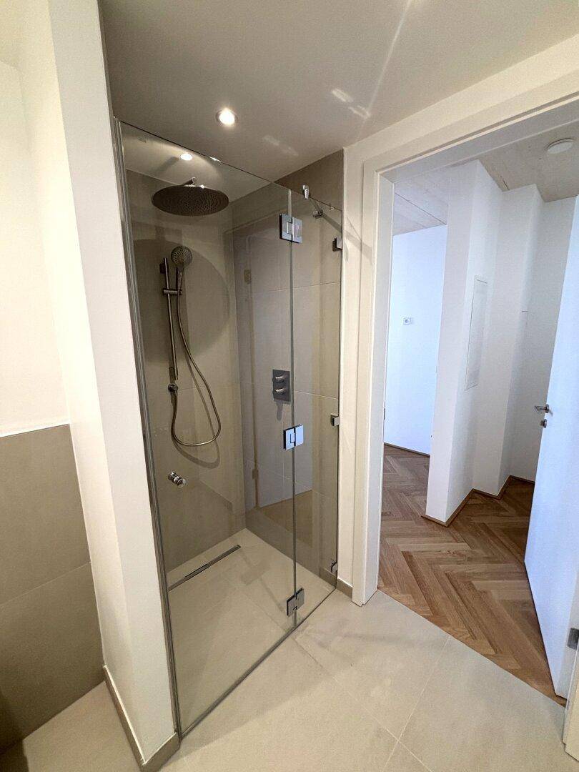 Elegante begehbare Dusche mit Glasabtrennung und Regenduschkopf in modernem Badezimmer.