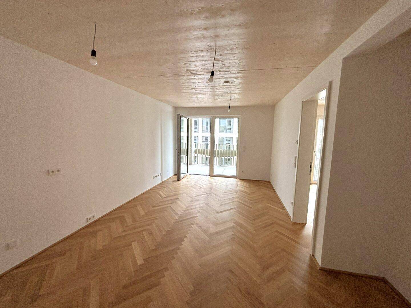 Geräumiges, helles Zimmer mit Fischgrätparkett und Schiebetür zum Balkon.