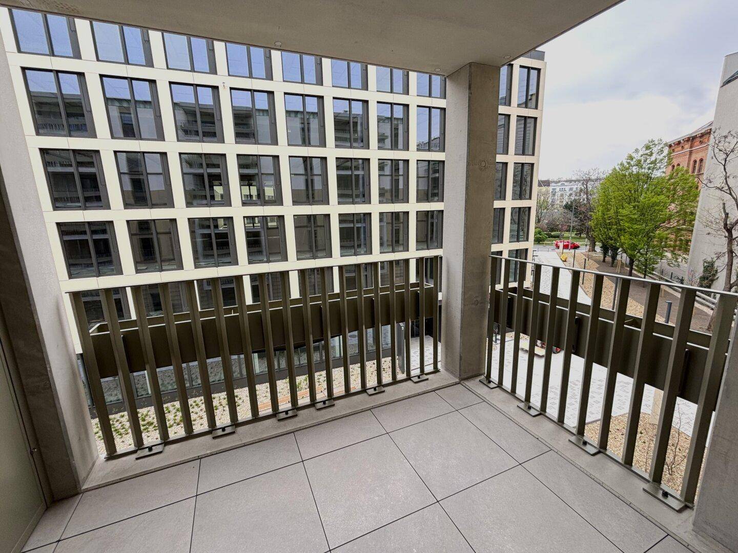 Geräumiger Balkon mit Fliesenboden und Blick auf die moderne Gebäudefassade.