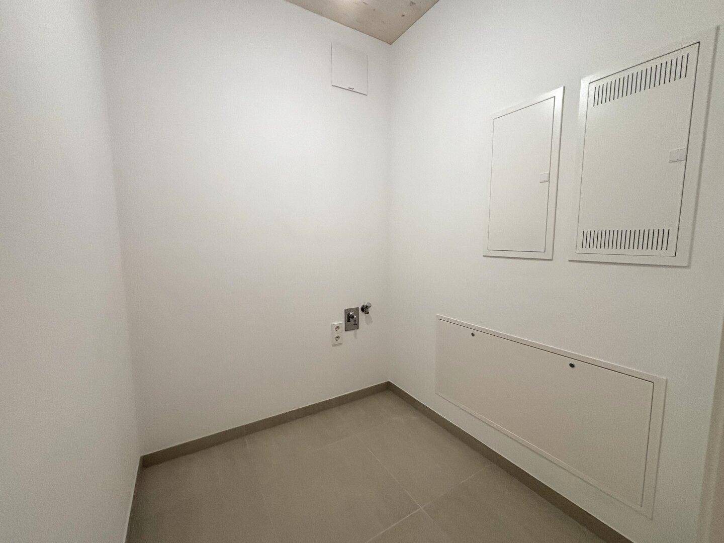 Praktischer Hauswirtschaftsraum mit Fliesenboden und Anschlüssen für Waschmaschine und Trockner.