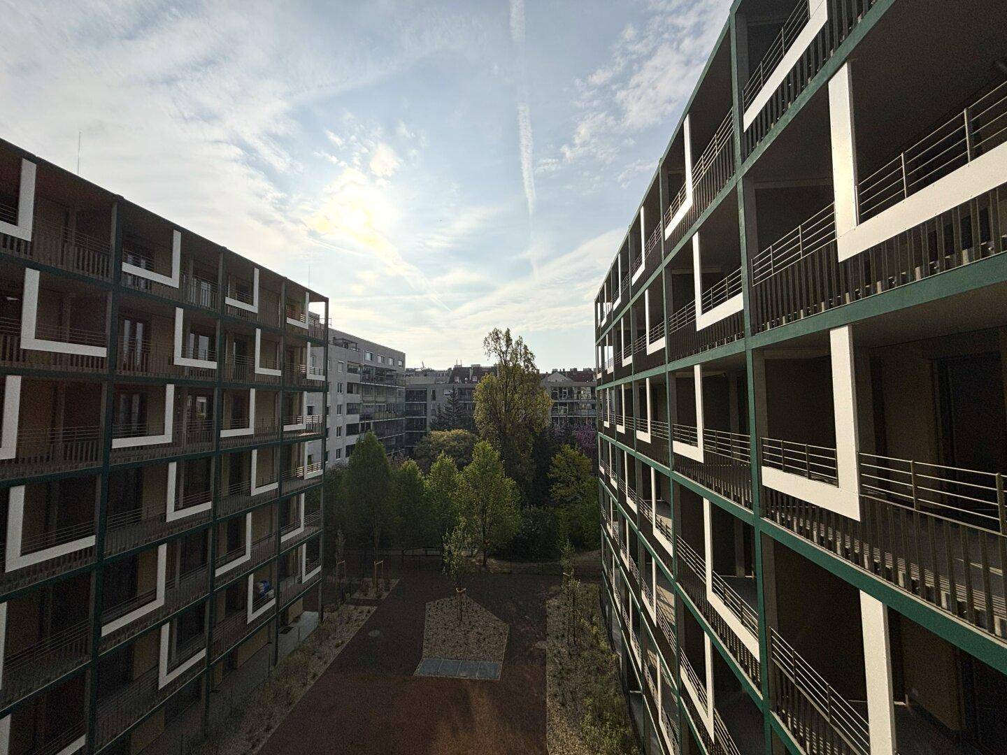 Moderne Wohngebäude mit Balkonen und begrüntem Innenhofbereich.