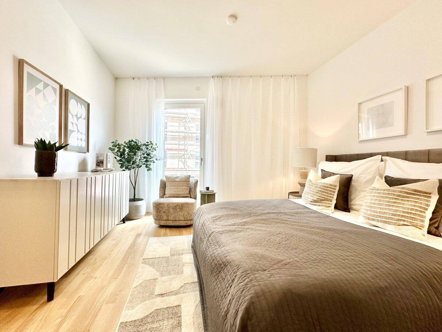 Geräumiges Schlafzimmer mit viel Tageslicht, Holzboden und einer gemütlichen Sitzecke am Fenster.
