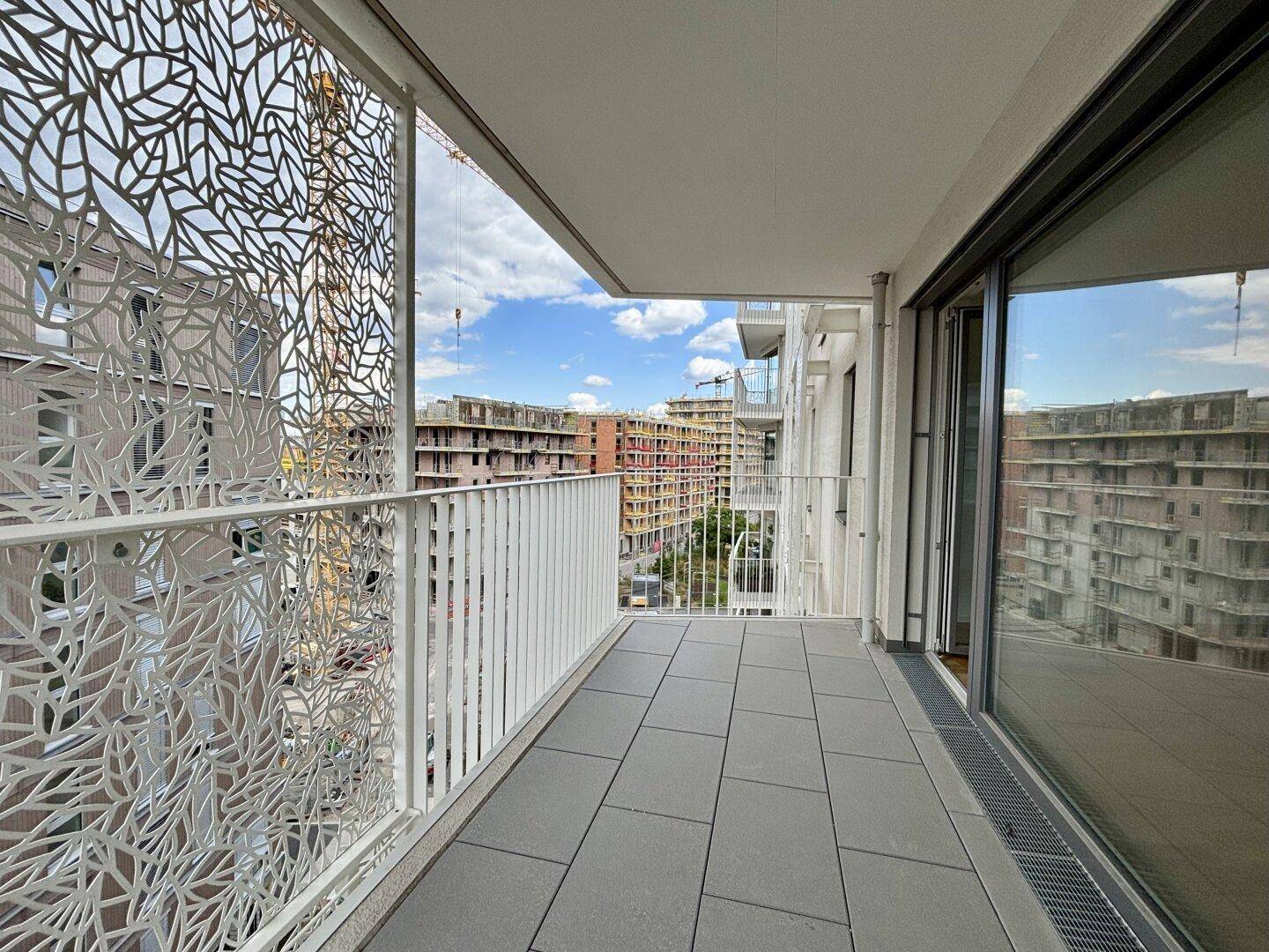 Geräumiger Balkon mit modernen Fliesen und dekorativem Geländer, bietet Blick auf die umliegenden Gebäude.