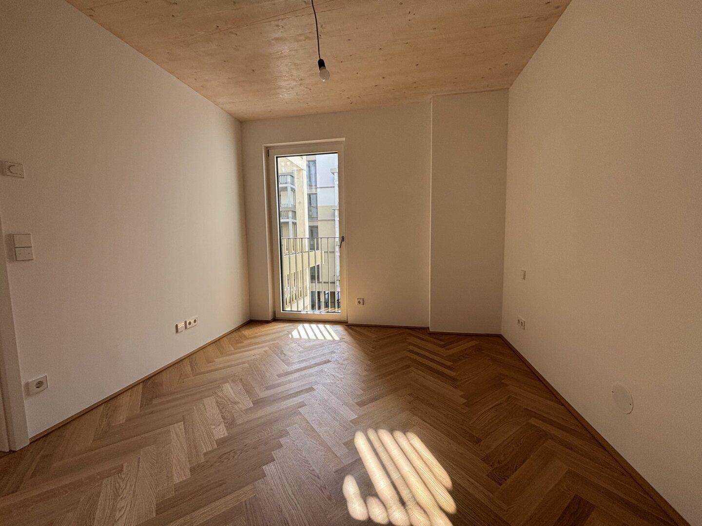 Gemütliches Zimmer mit Fischgrätparkett und französischem Balkon, bietet viel Tageslicht.
