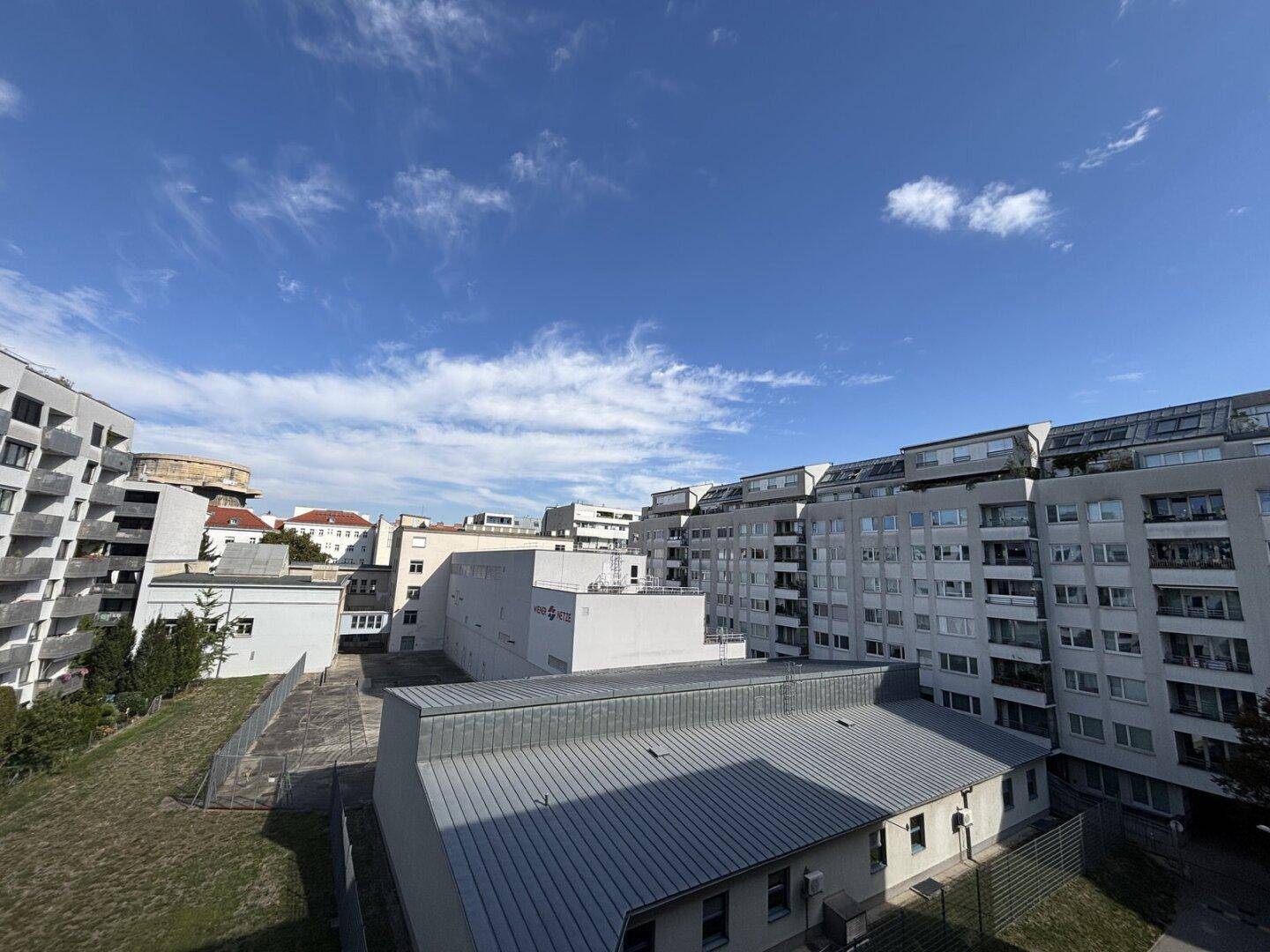 Blick auf die umliegenden Wohngebäude und den blauen Himmel über der Stadt.