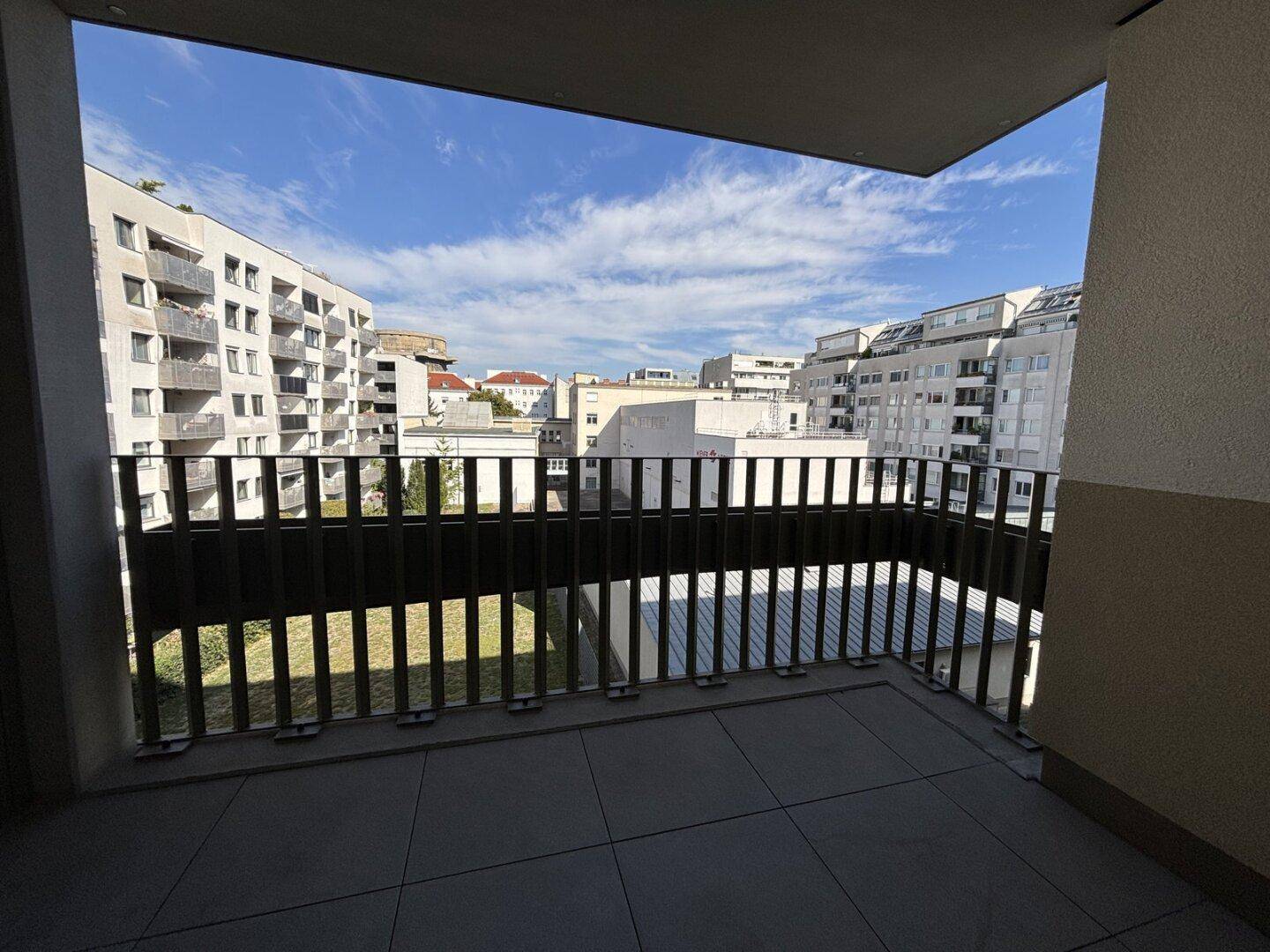 Balkon mit Blick auf die umliegenden Wohngebäude und den blauen Himmel.