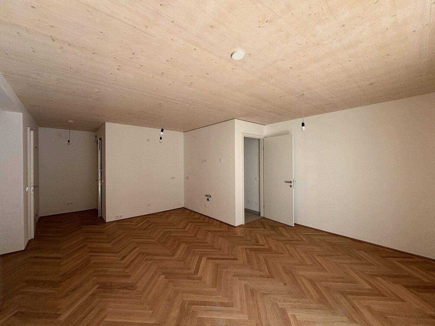 Großzügiger, heller Raum mit Fischgrätparkett und Holzbalkendecke, bereit zur individuellen Gestaltung.