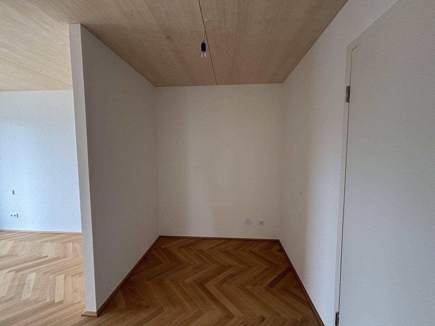 Kleiner, unmöblierter Raum mit Holzdeckenverkleidung und Fischgrätparkettboden.