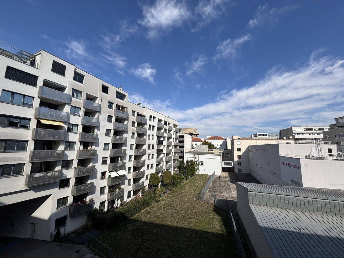 Mehrfamilienhaus mit zahlreichen Balkonen und Blick auf die umliegende Stadtlandschaft.