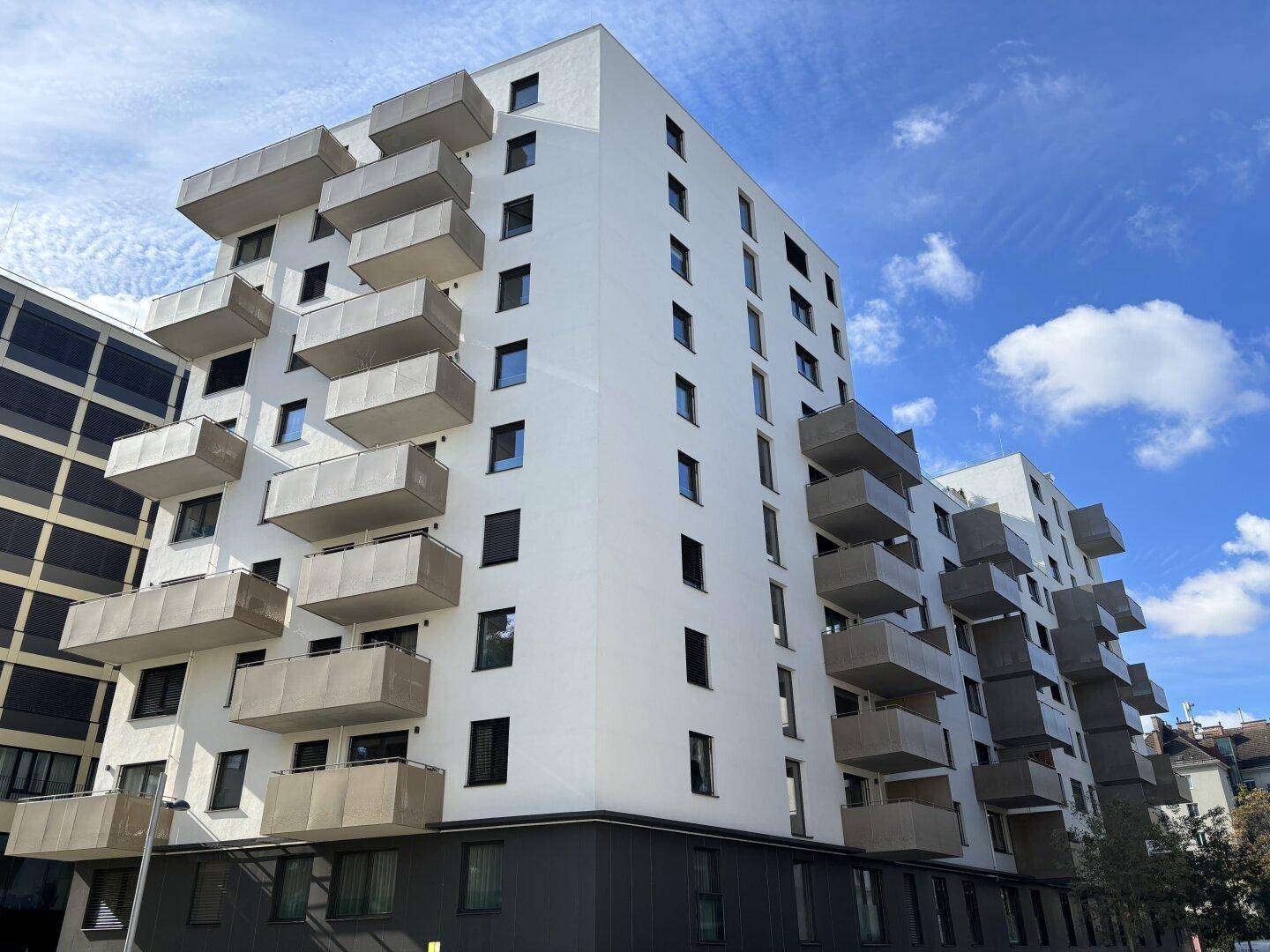Neubau-Apartmentgebäude mit markanten Balkonen und einer Kombination aus weißen und grauen Fassaden.