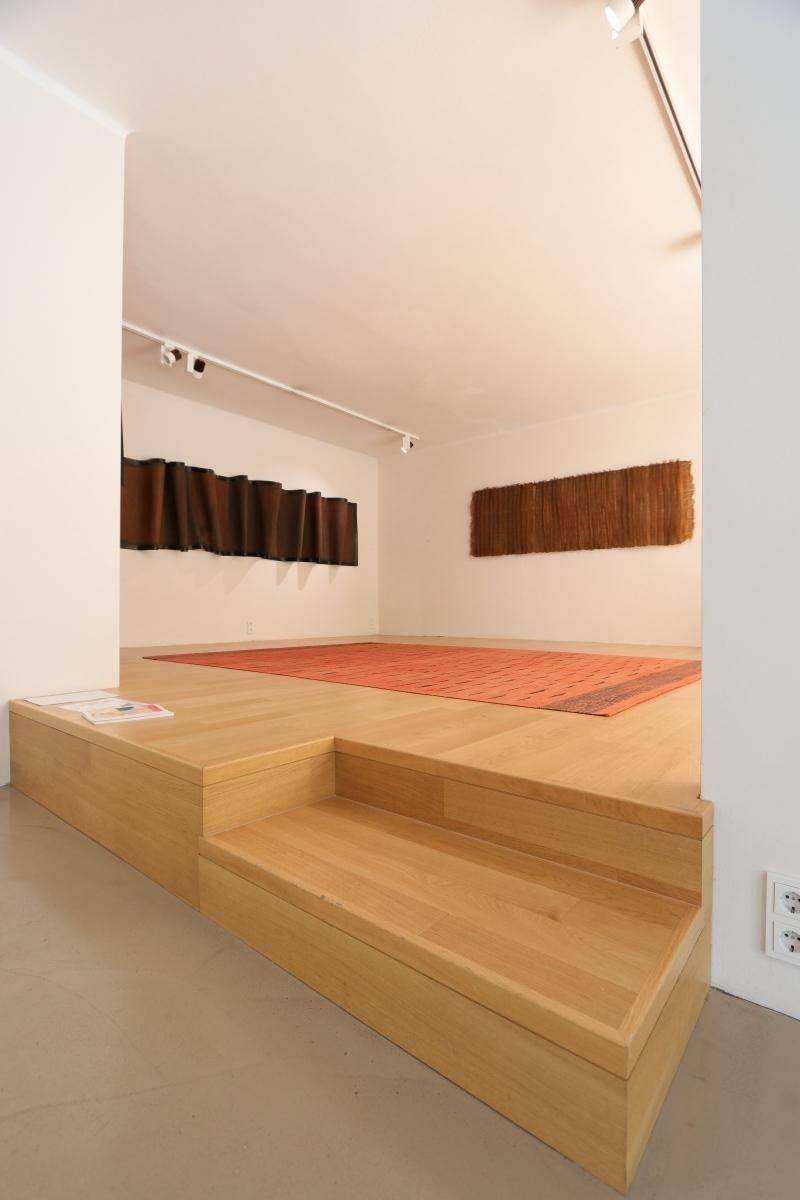 Erhöhte Holzplattform mit Stufen und einem roten Teppich, ideal für Präsentationen oder Ausstellungen.
