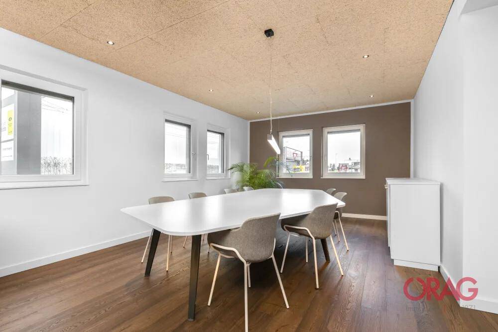 Geräumiger Besprechungsraum mit Holzboden, Akustikdecke und einem großen, modernen Konferenztisch.