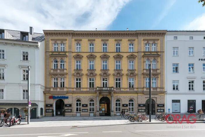 Historisches Gebäude mit aufwendiger Fassade, vielen Fenstern und einem kleinen Balkon im Zentrum.