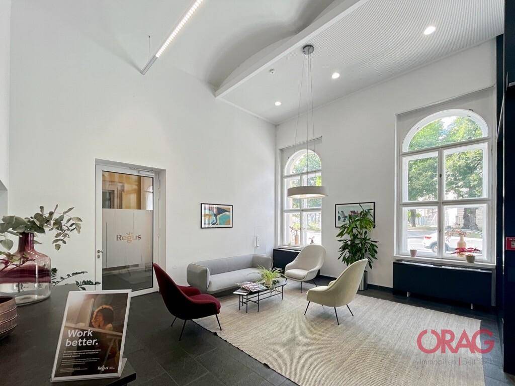 Geräumiger Empfangsbereich mit hohen Decken, modernen Möbeln und großen Bogenfenstern.