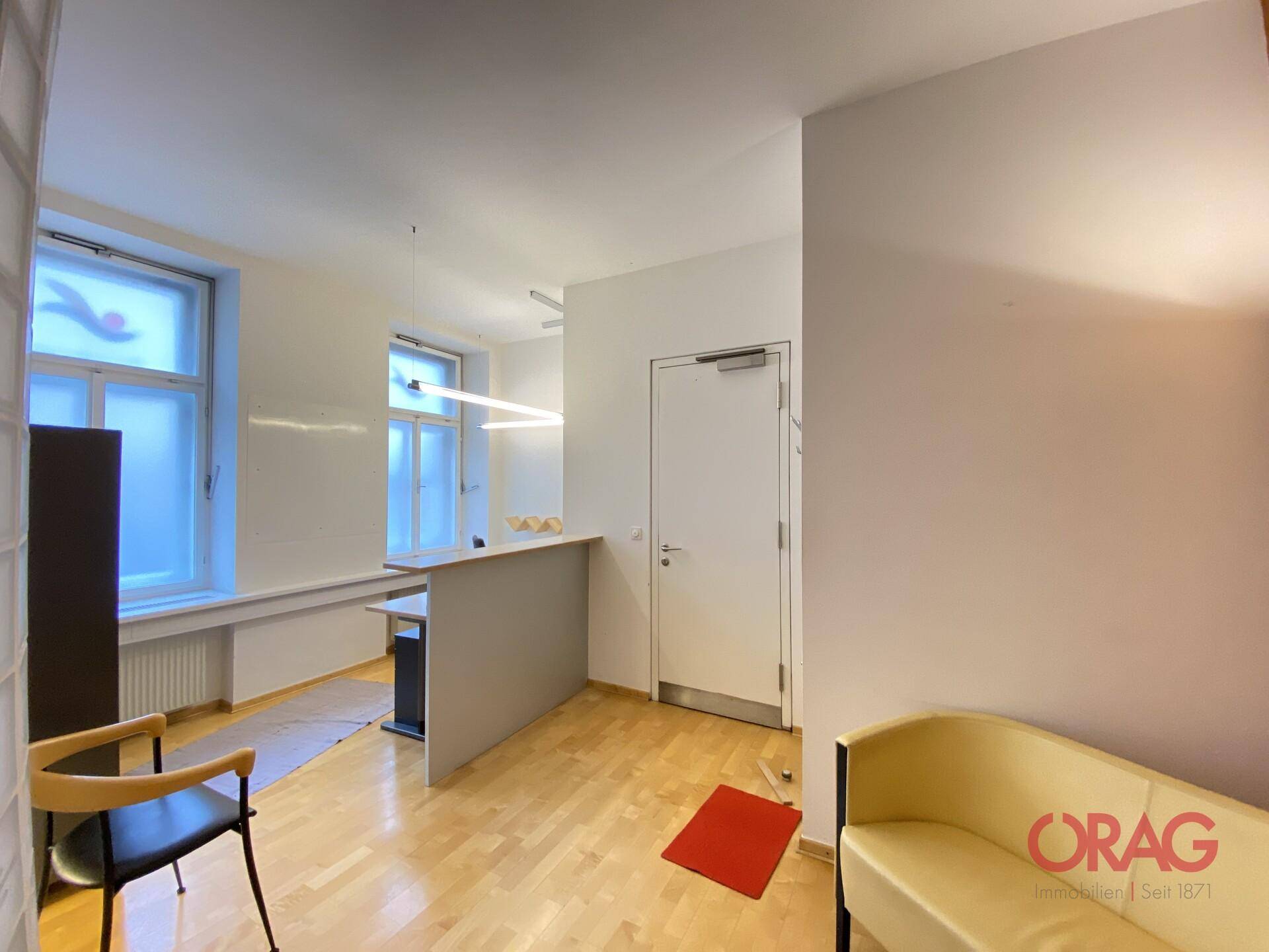 Empfangsbereich mit Theke, Sitzgelegenheit und Fenster, einladend und funktional gestaltet.