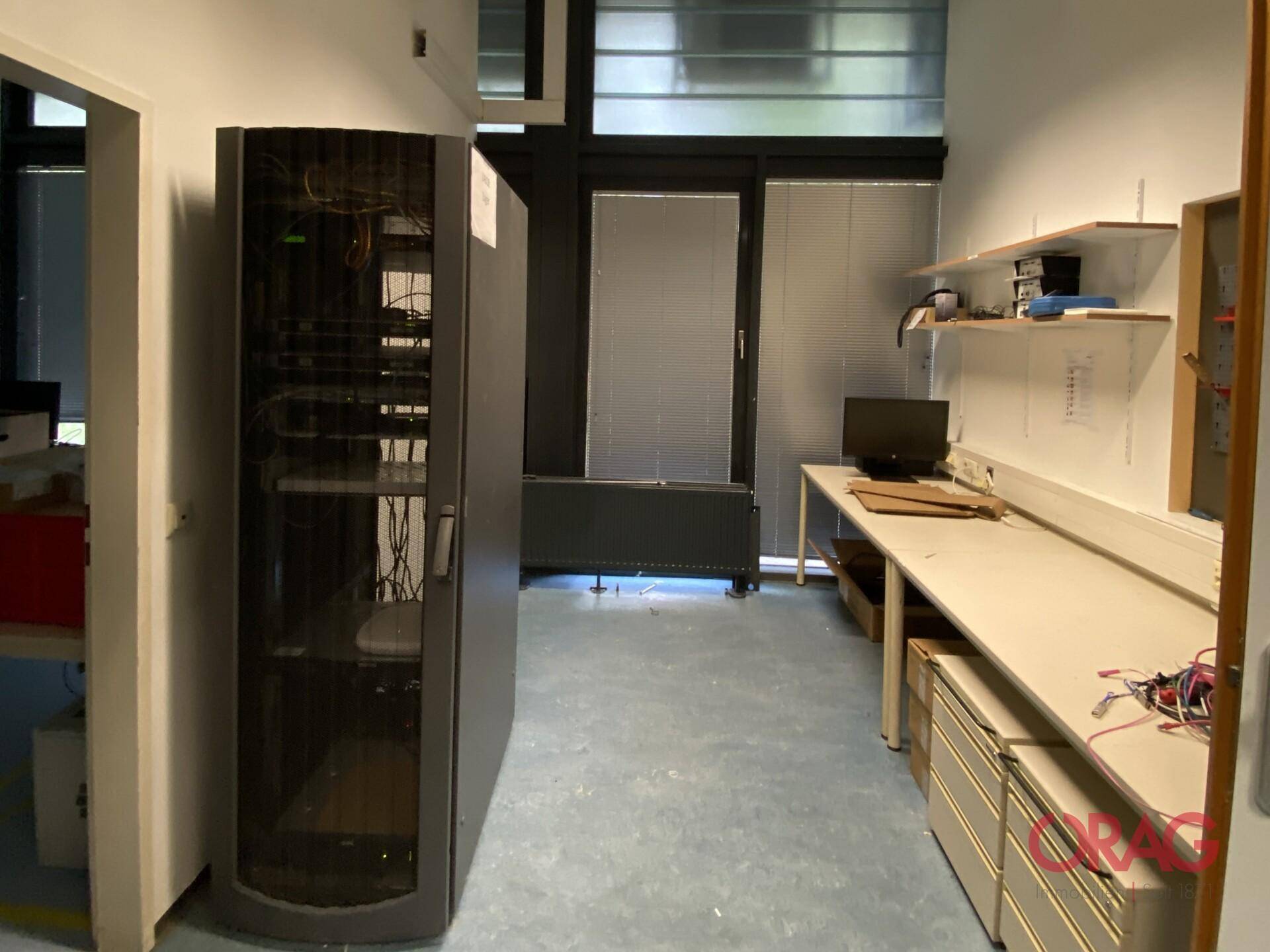 Lagerraum mit Serverrack, Werkbank und großen Fenstern, die natürliches Licht hereinlassen.