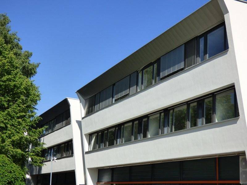 Seitenansicht eines modernen Bürogebäudes mit vielen Fenstern und klarem Himmel.