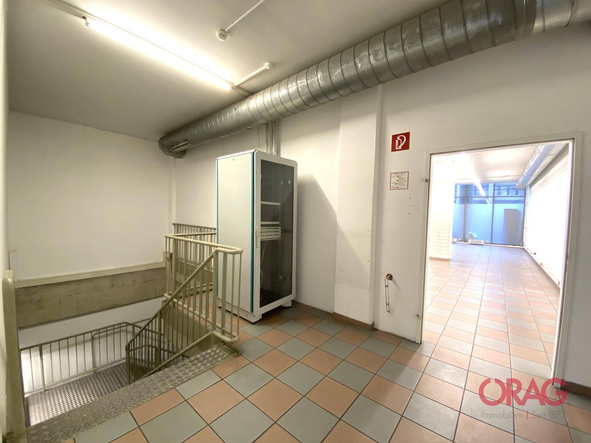 Treppenabsatz mit Metallgeländer, Fliesenboden und einem Serverschrank.