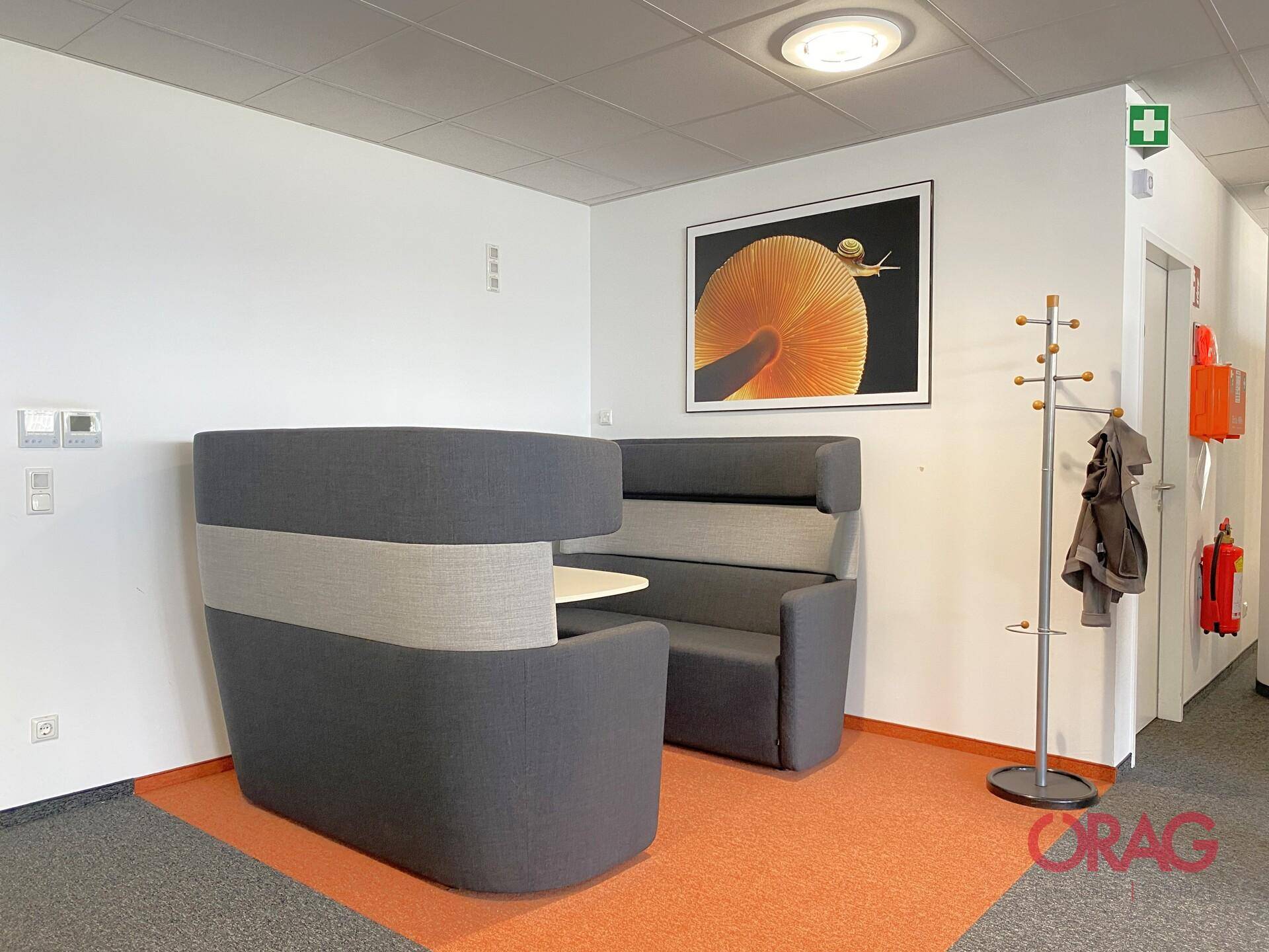 Gemütliche Lounge-Ecke mit gepolsterten Sitzgelegenheiten und einem Kunstwerk an der Wand.