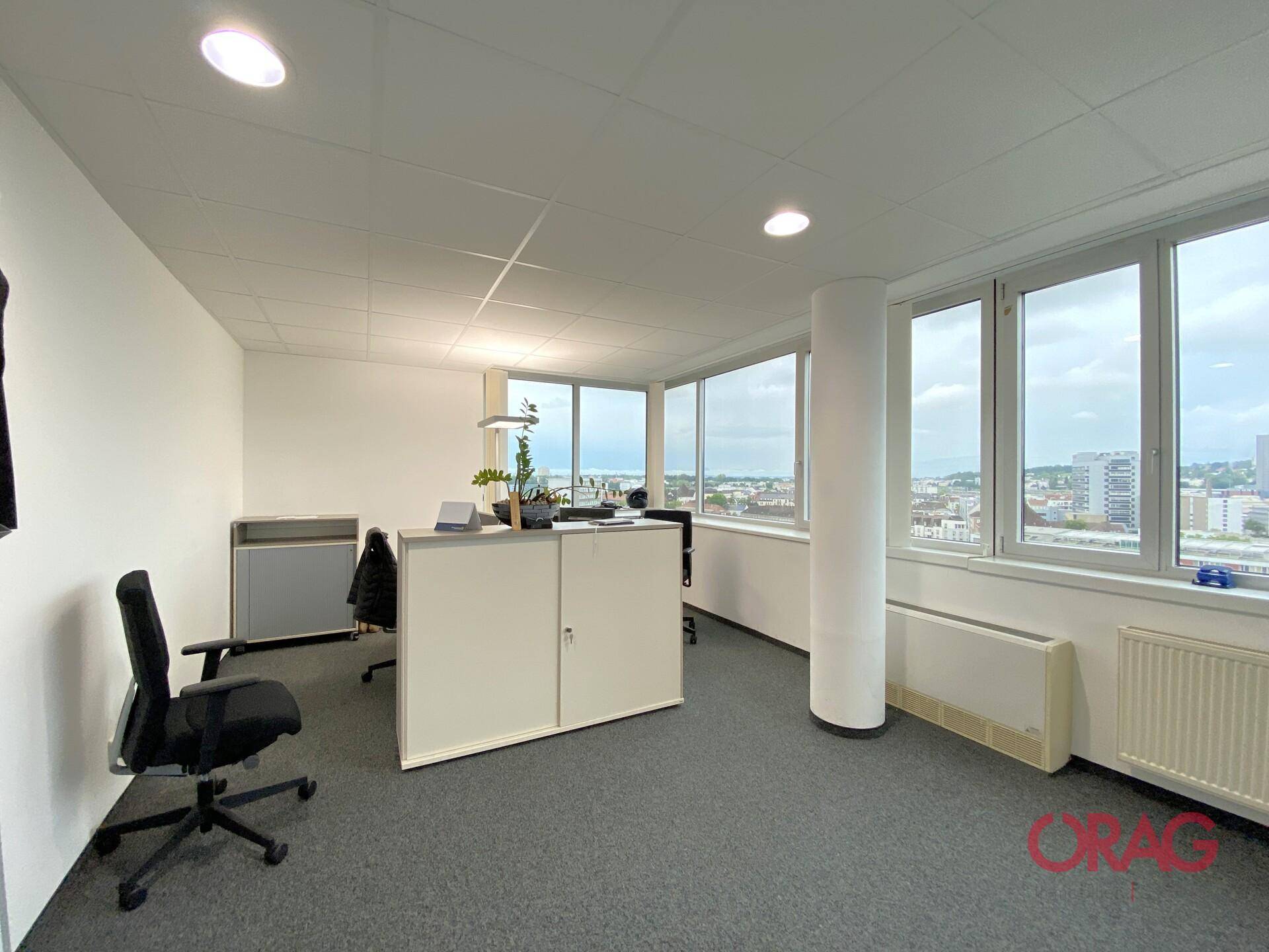 Helles Einzelbüro mit großen Fenstern, die einen weiten Blick über die Stadt und die Umgebung bieten.