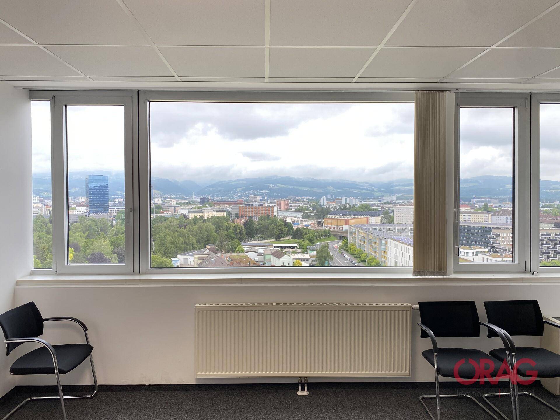 Große Fensterfront mit weitem Stadt- und Bergblick, ideal für ein helles Büro.