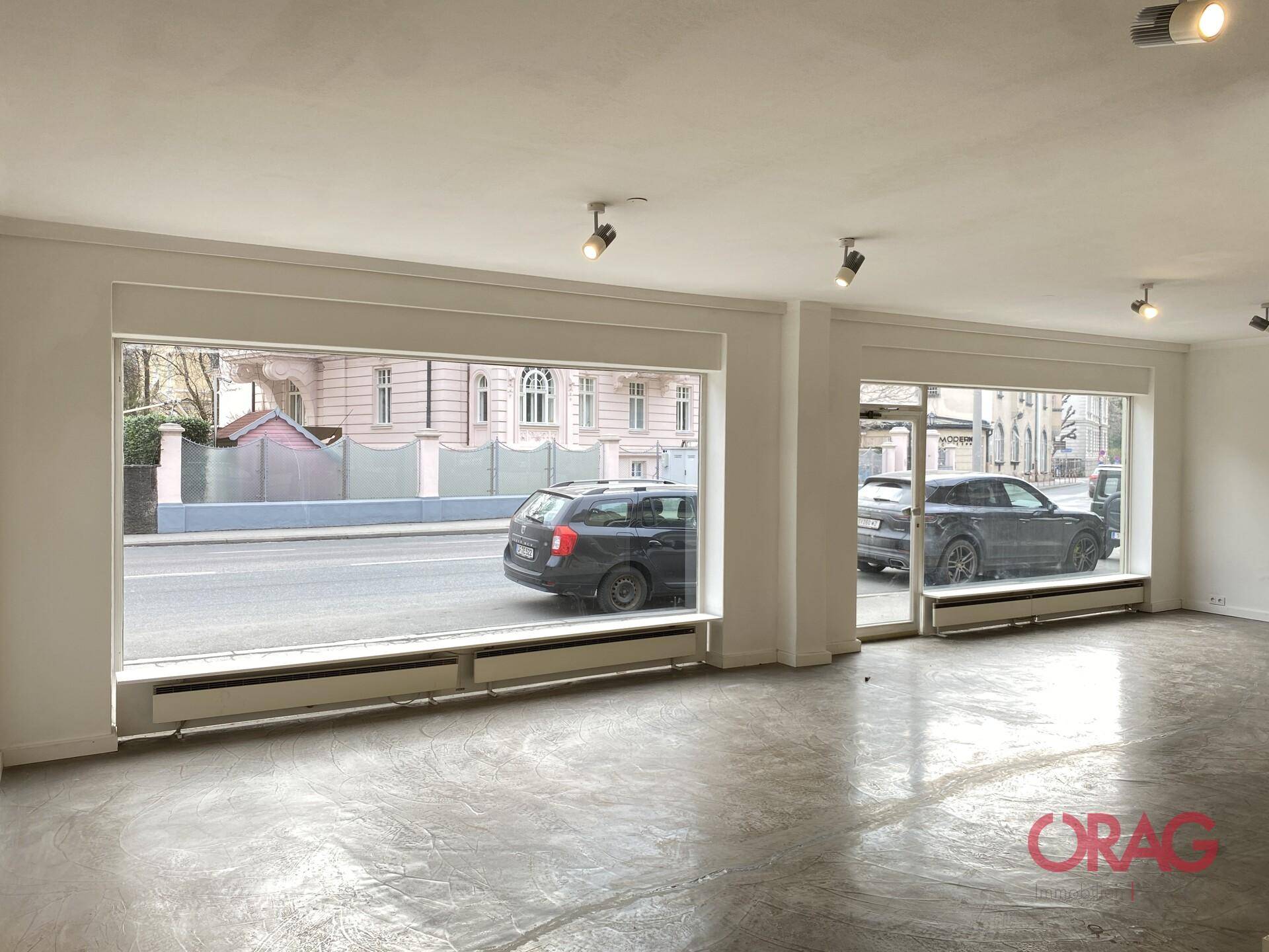 Heller Gewerberaum mit großen Schaufenstern, die einen Blick auf die belebte Straße bieten.