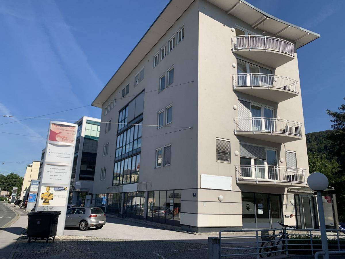 Modernes Geschäftsgebäude mit mehreren Balkonen und großen Fensterfronten an einer städtischen Straße gelegen.