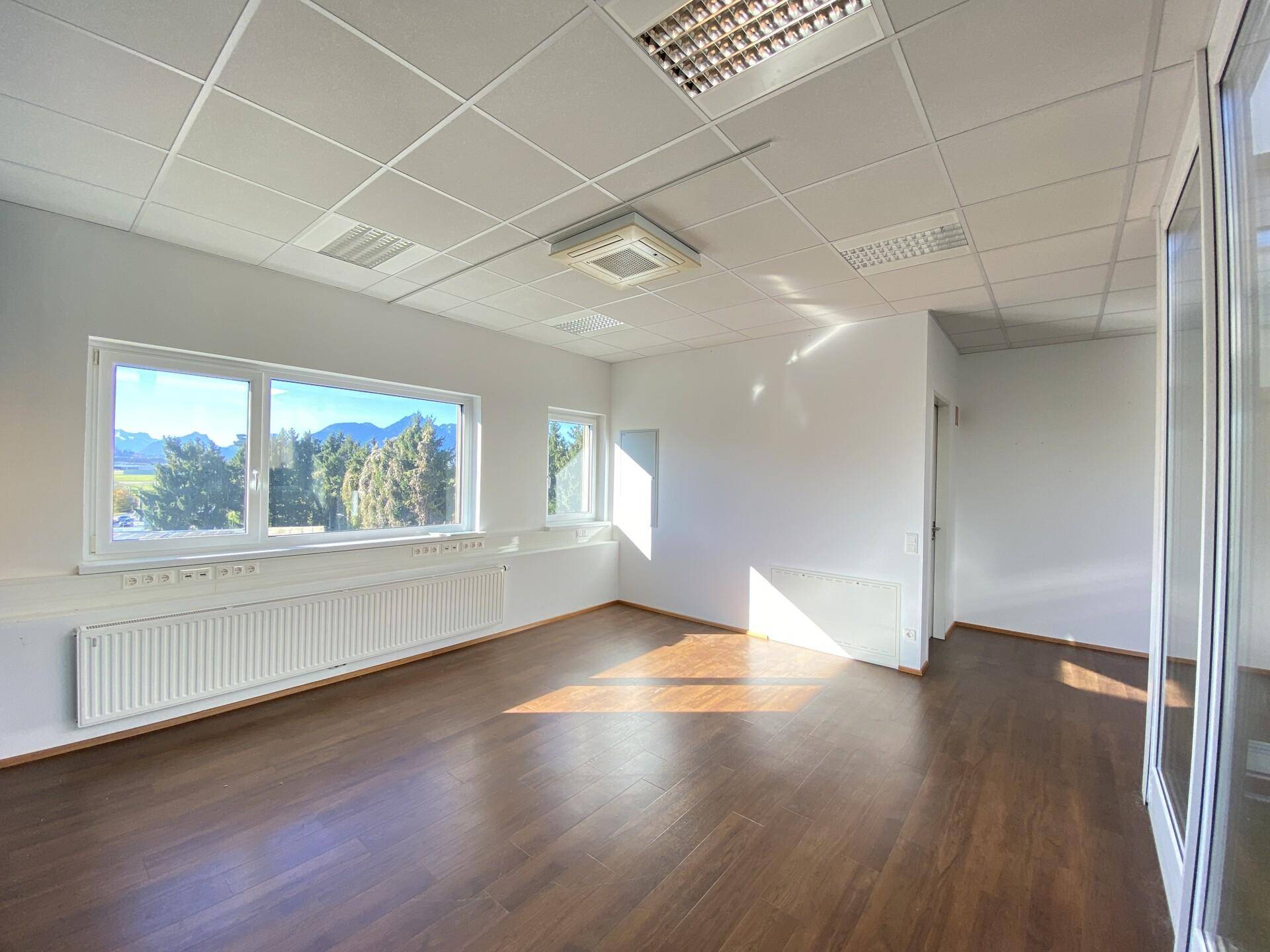 Helles Büro mit Holzboden und Fenstern, die einen weiten Blick auf die Berge und die umliegende Landschaft bieten.