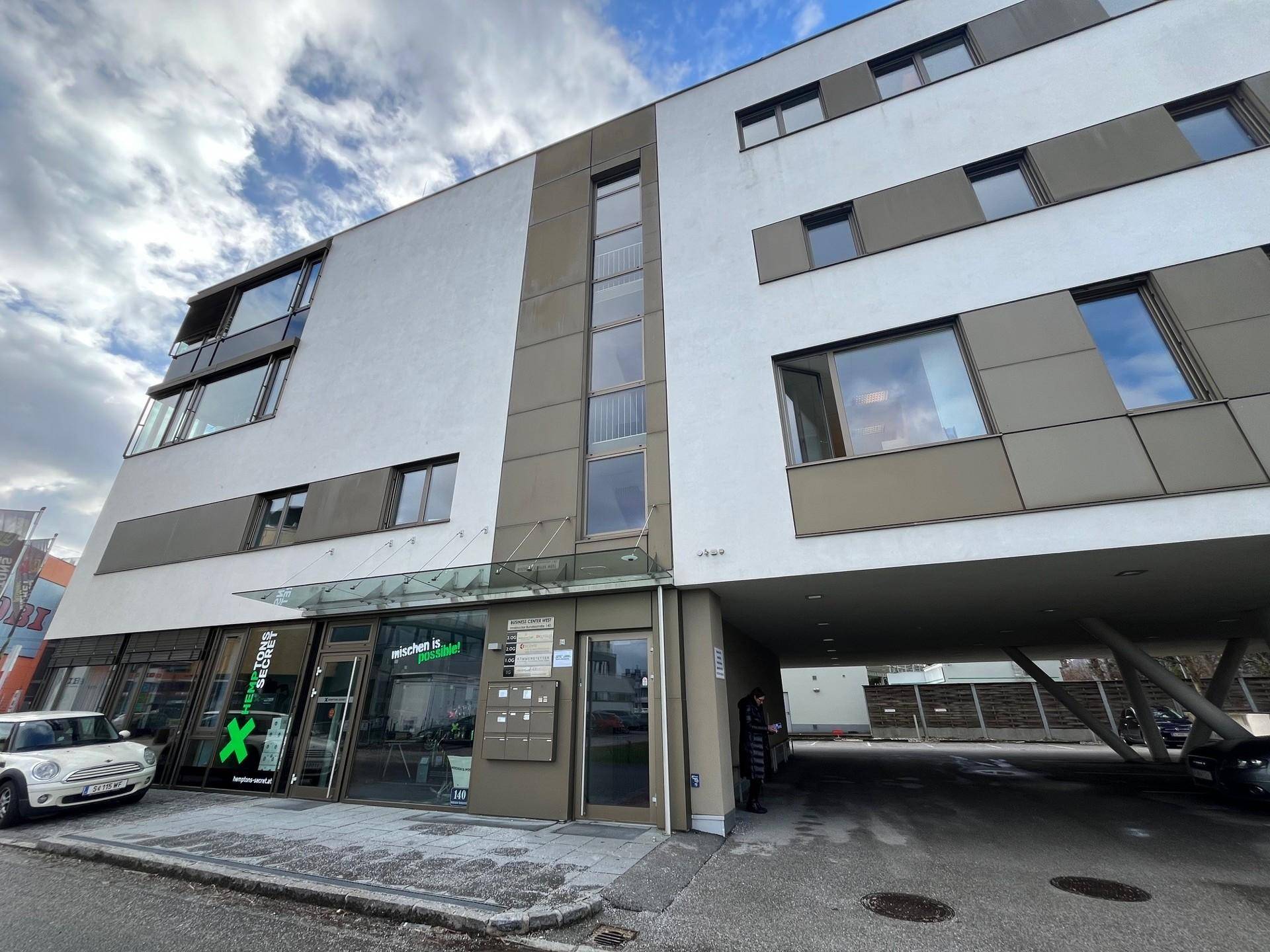 Moderne Geschäftsfassade mit großen Fenstern und einem überdachten Eingangsbereich.