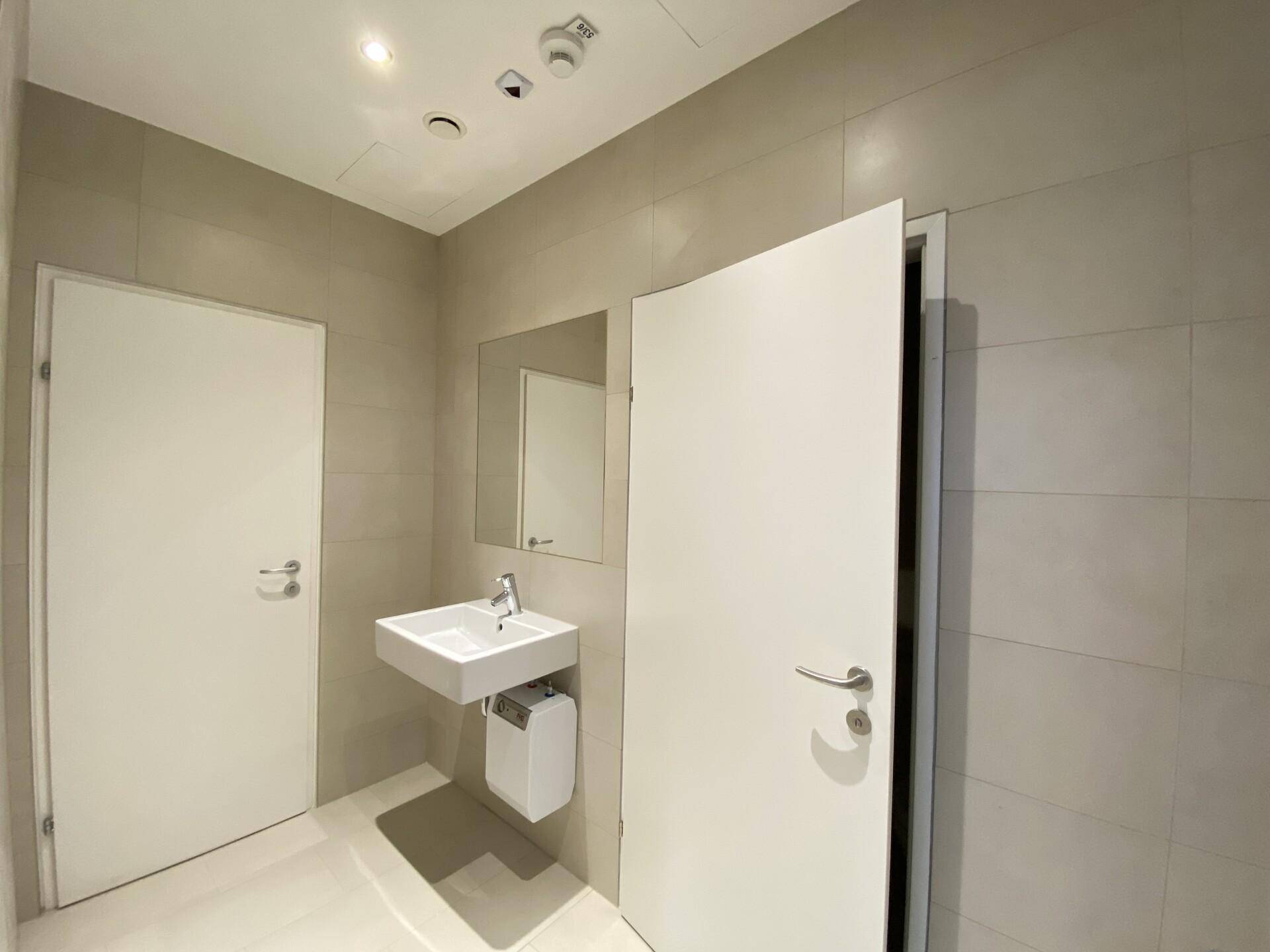 Modernes Badezimmer mit schwebendem Waschbecken, Spiegel und hellen Fliesen, in sehr gutem Zustand.