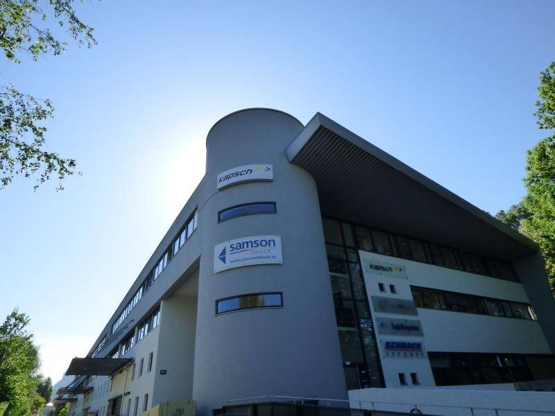 Zeitgenössisches Bürogebäude mit runden und eckigen Elementen unter strahlend blauem Himmel.