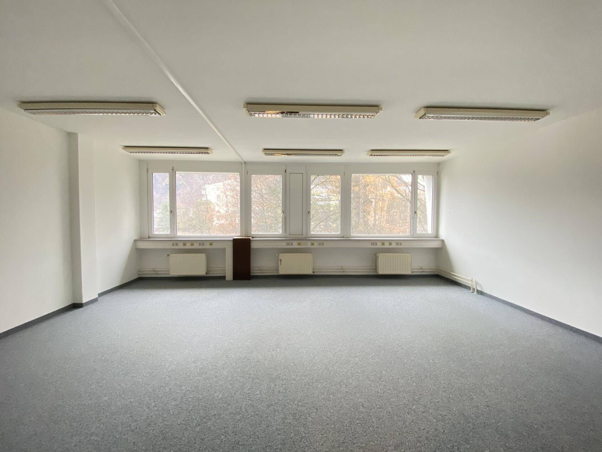 Großes, helles Büro mit vielen Fenstern und Teppichboden, bereit für die individuelle Gestaltung.
