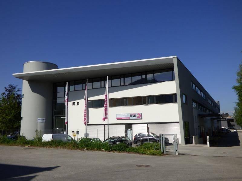 Modernes Geschäftsgebäude mit großen Glasflächen und klaren Linien unter blauem Himmel.