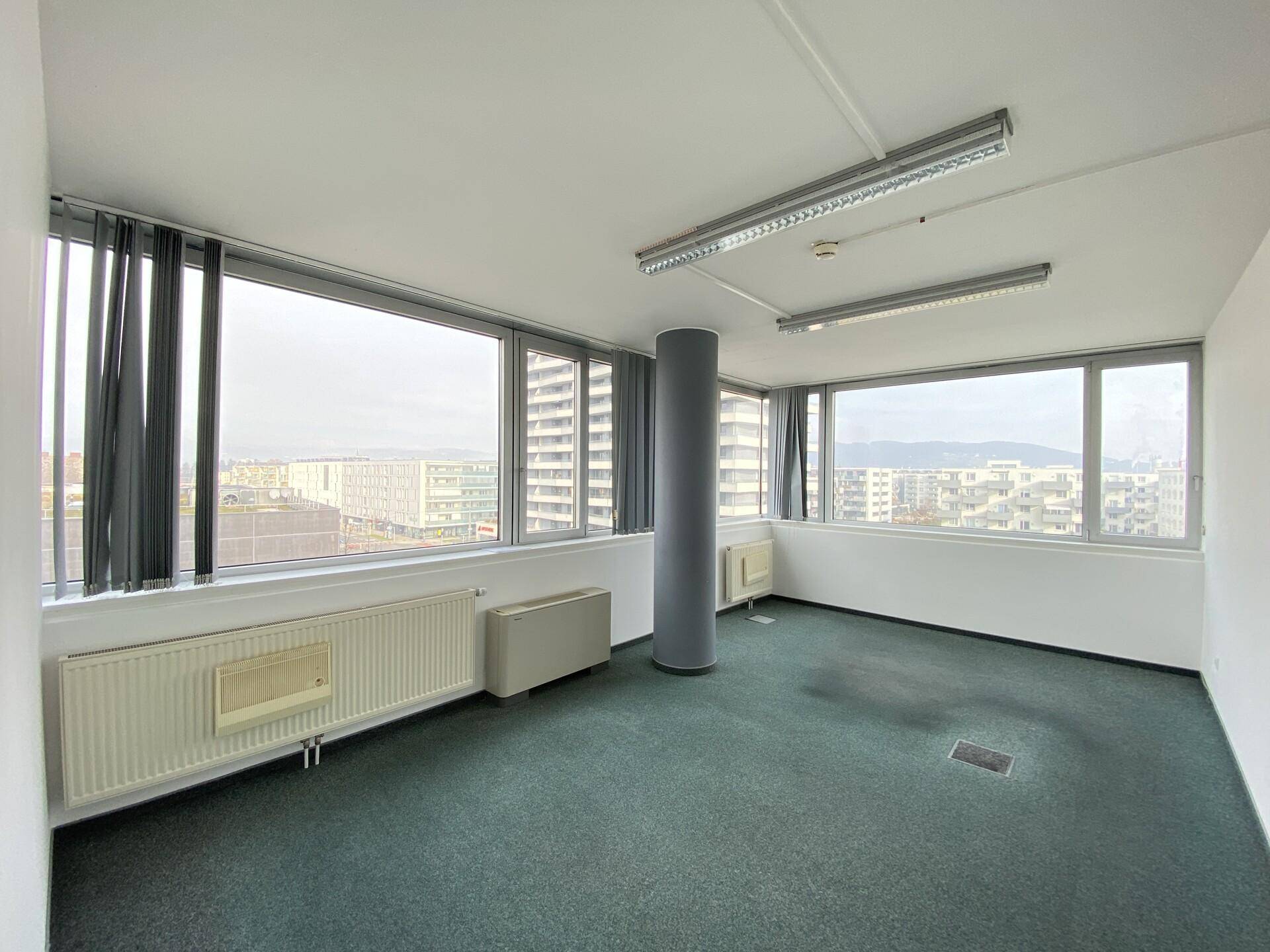Helles Büro mit großen Fenstern und Teppichboden, bietet einen weiten Blick über die Stadt.