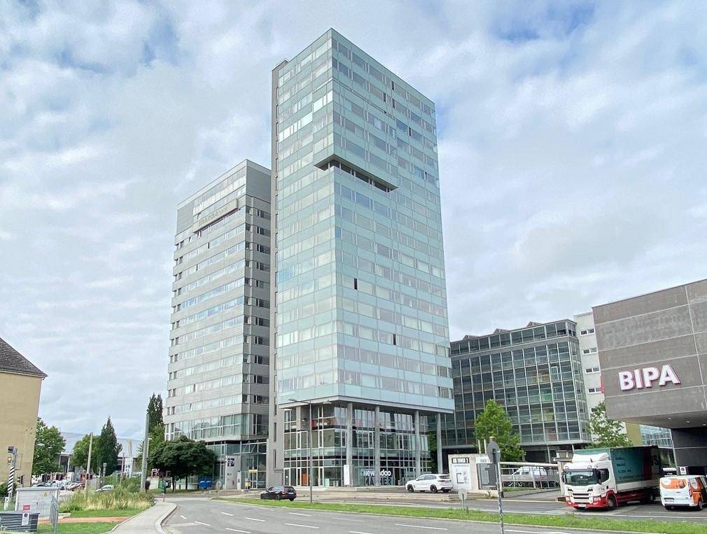 Modernes Hochhaus mit Glasfassade und umliegender Stadtlandschaft, prägt das Stadtbild.