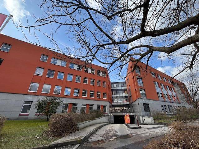 Großes Bürogebäude mit roter Fassade, vielen Fenstern und einer Zufahrt zur Tiefgarage.