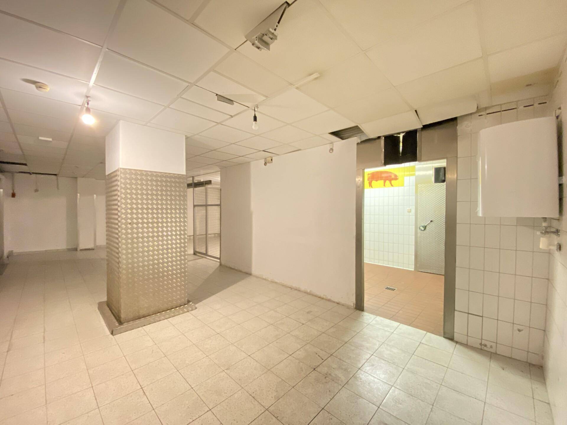 Kellerraum mit Fliesenboden, Warmwasserbereiter und Zugang zu einem gefliesten Nebenraum.