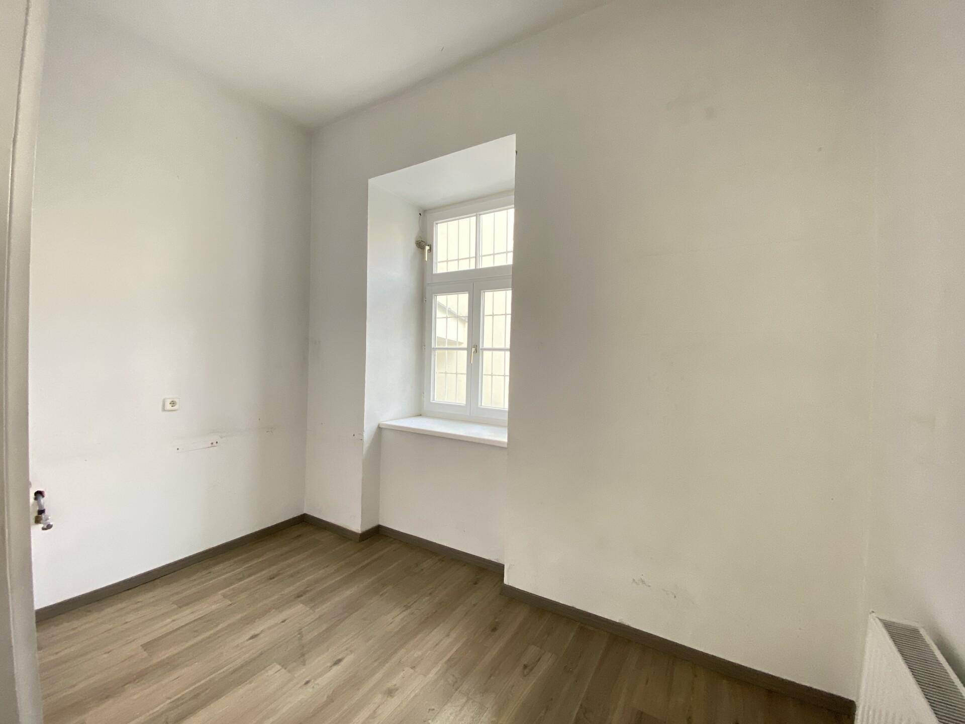 Ruhiger Büroraum mit Laminatboden und einem Fenster, ideal für konzentriertes Arbeiten.