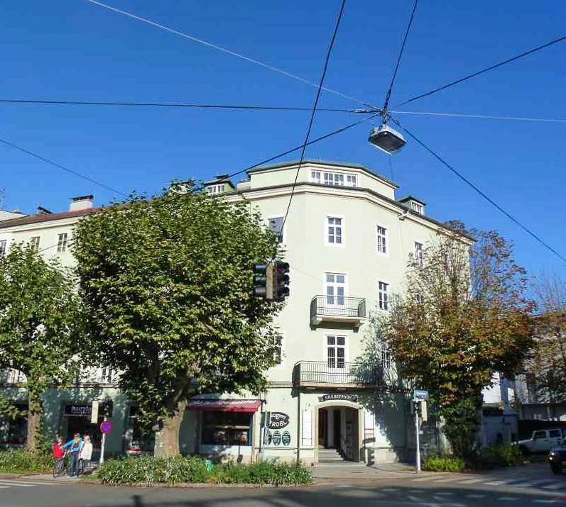 Historisches Eckgebäude mit klassischer Architektur und Bäumen an einer städtischen Straße.