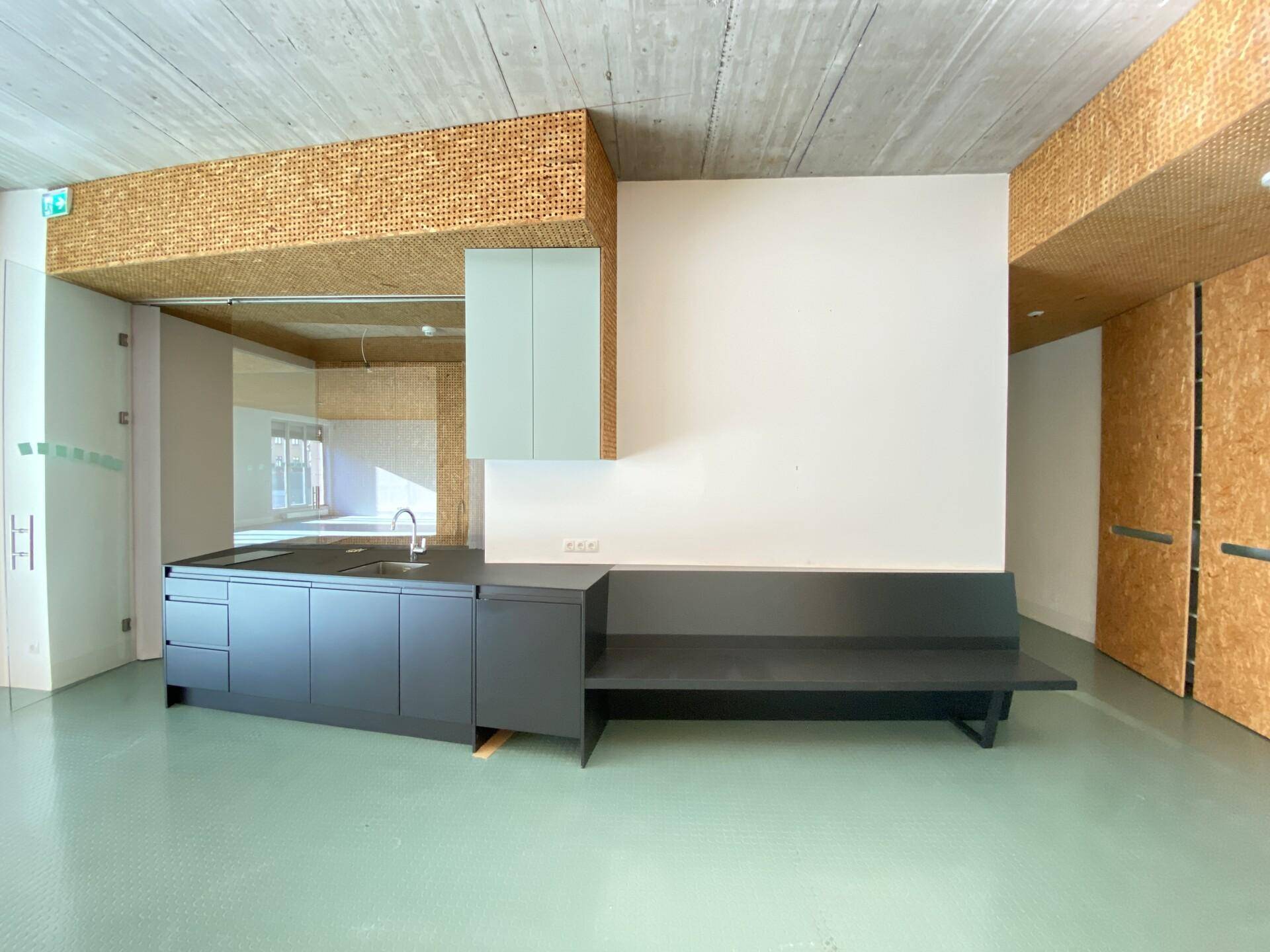 Moderne Teeküche mit dunklen Schränken, integrierter Sitzbank und Holzverkleidung.