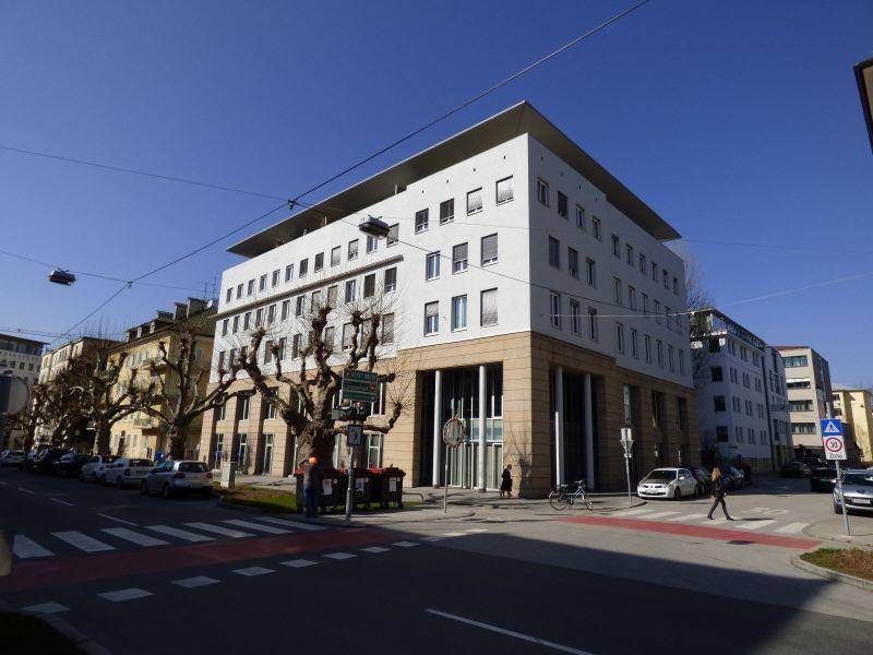 Modernes Bürogebäude an einer belebten Straße mit klaren Linien und großen Fenstern.