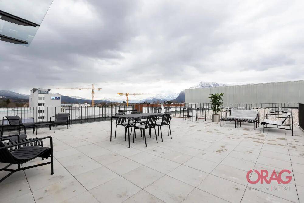 Geräumige Dachterrasse mit modernen Gartenmöbeln und weitem Blick auf die Berge und die Stadt.