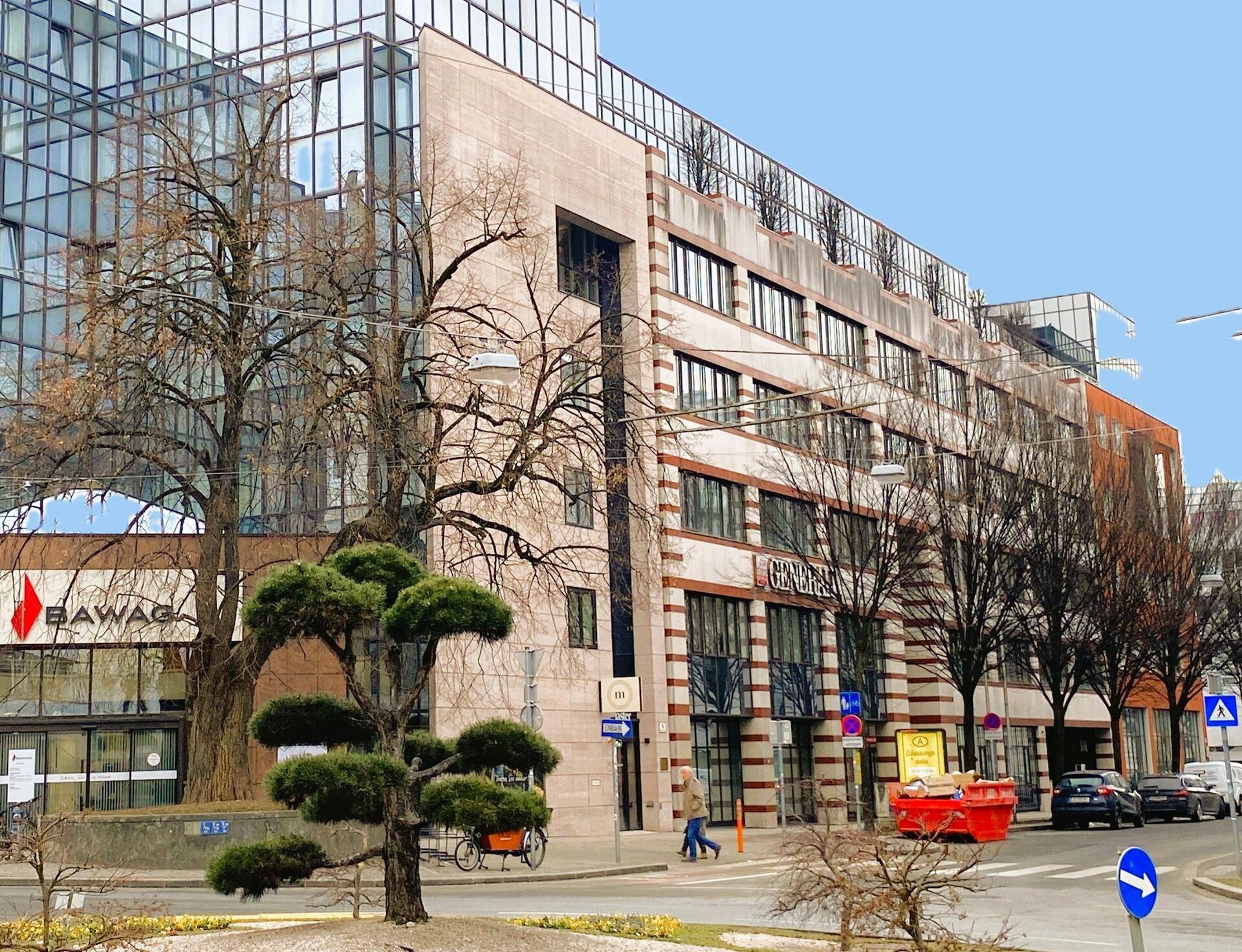 Moderne Bürogebäude-Fassade mit großen Glasflächen und traditionellen Elementen an einer belebten Straße.