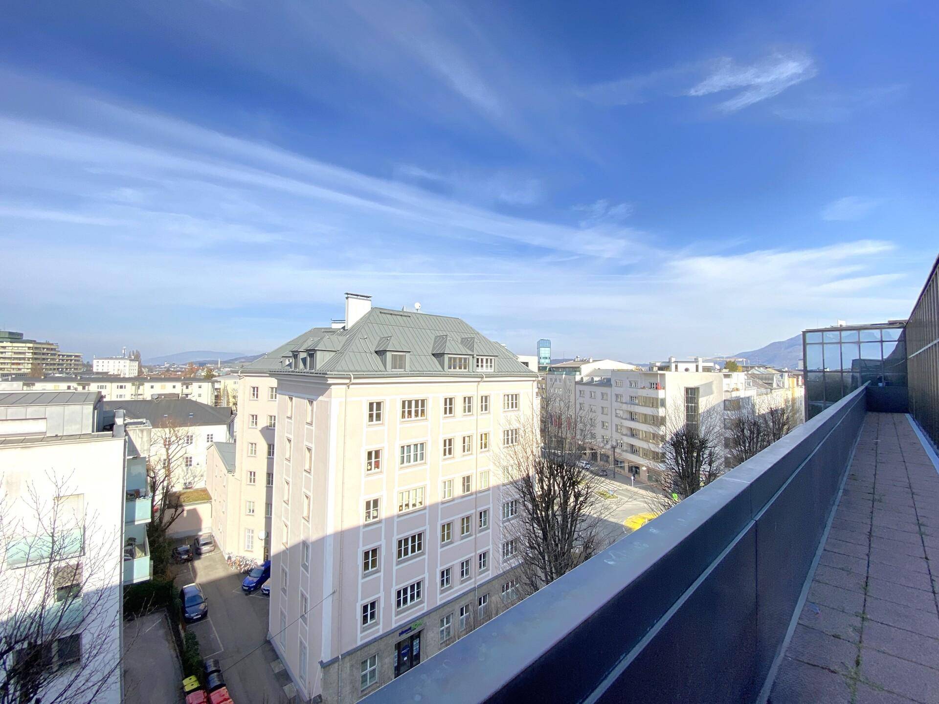 Weitblick über die Stadt mit verschiedenen Gebäuden und einem klaren blauen Himmel von einer erhöhten Position.