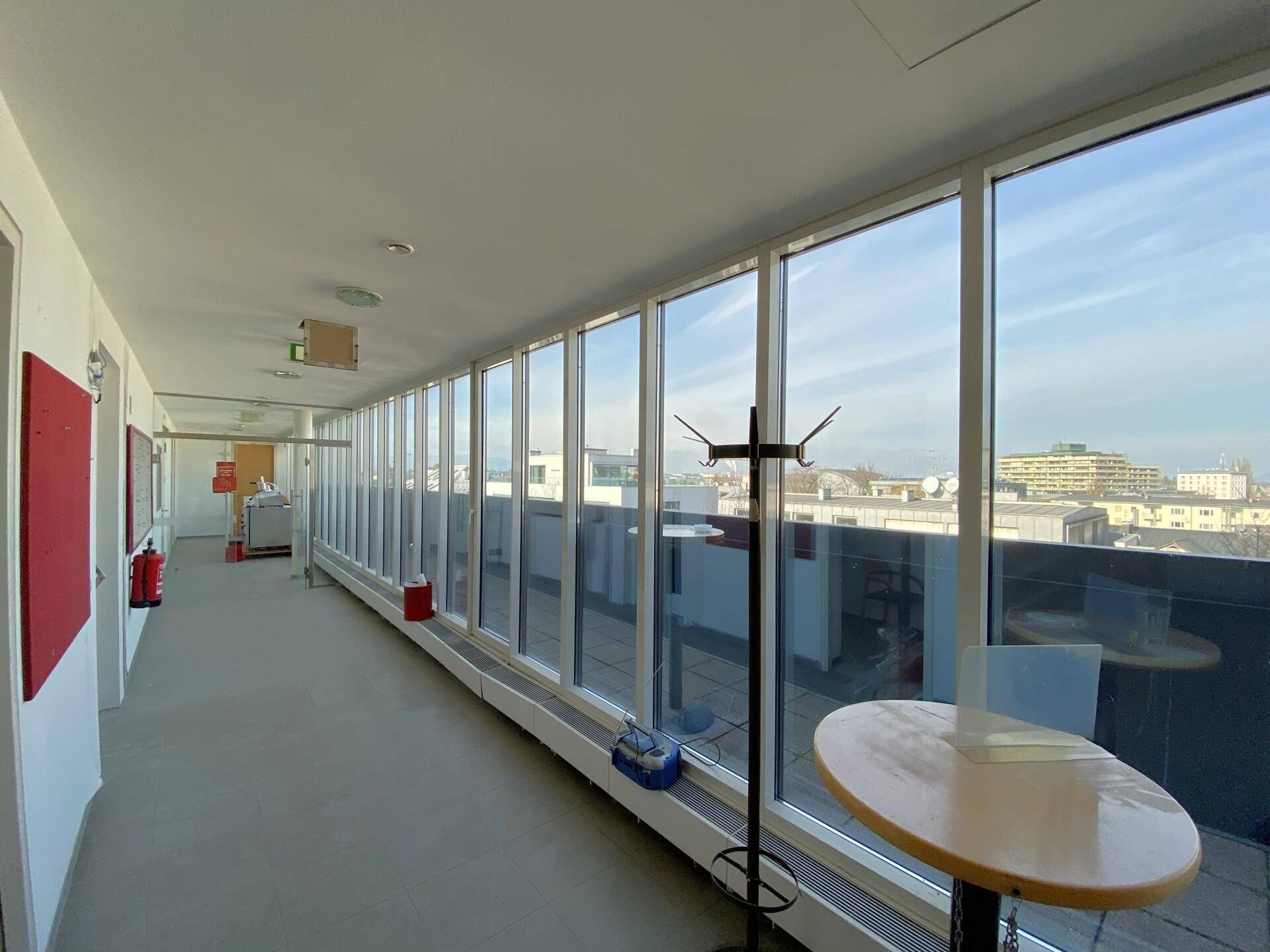 Heller Büroflur mit großen Fensterfronten, die einen weiten Blick über die Stadt bieten.